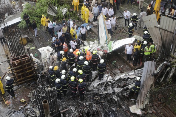 Rescuers stand amid the wreckage of a private chartered plane that crashed in Ghatkopar area, Mumbai, India, Thursday, June 28, 2018. (AP Photo/Rajanish Kakade)