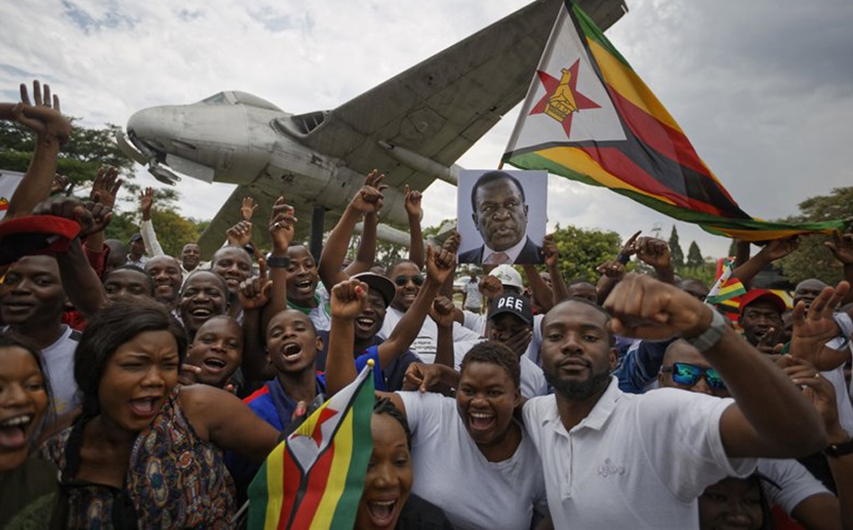 Supporters of Emmerson Mnangagwa, the man expected to become Zimbabweâ€™s new president, hold a photograph of him and cheer as they arrive to show their support at Manyame Air Force base (AP Photo)